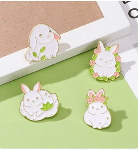 Detail of four cute white rabbit enamel pins with gold plating and floral accents