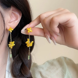Elegant floral pearl earrings with yellow blossoms and green pendant on a female model