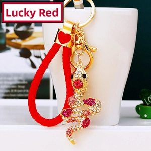 Macro shot of a golden snake keychain with rhinestones and red braided leather cord