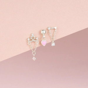 Detail of S925 silver earrings with heart, crown, and pearl charms on pink background