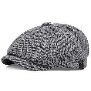 Detail of herringbone wool newsboy cap featuring leather trim and a metallic button