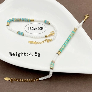 Bohemian beaded bracelet with turquoise tube beads and gold accents on a ceramic plate
