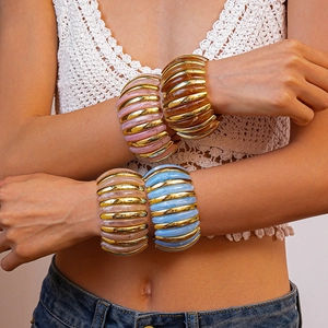 Close-up of four chunky striped acrylic bangles in mixed colors worn by a model