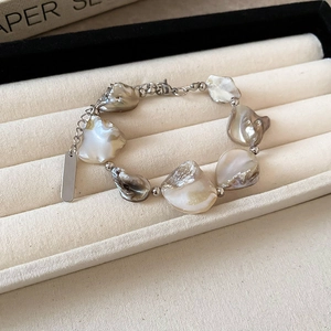 Dettaglio del bracciale con conchiglie e perle e chiusura a moschettone su vassoio