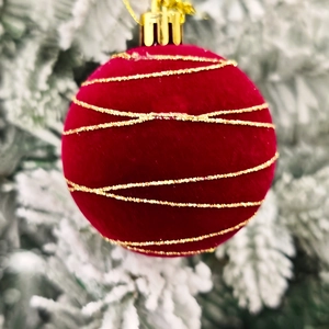 Détail d'une boule de Noël en velours rouge avec des lignes dorées en spirale