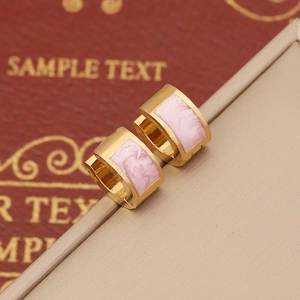 Detail shot of golden hoop earrings featuring pink marble inlay on a display stand