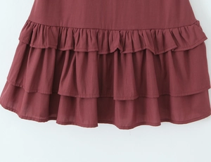 Detailed view of the burgundy layered ruffle hem and textured fabric of the summer dress