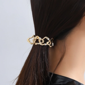Golden heart-shaped hair claw clip with rhinestones worn on a high ponytail