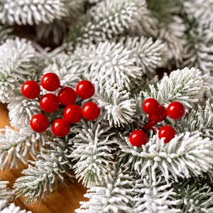 Artificial Christmas pine branches with red berries and snowy needles for festive decor