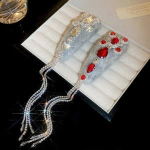 Detail of plush grey hair clips featuring red rhinestones and long glittering tassels