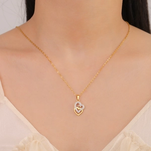 Macro detail of model wearing gold double heart pendant necklace with white crystals