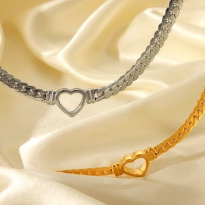 Close-up of gold and silver heart necklaces on champagne silk background