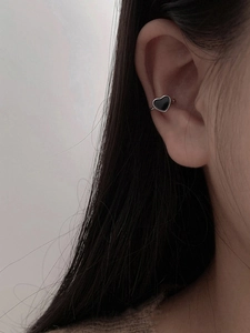 Close-up of a silver-toned metal ear cuff featuring a black heart enamel detail
