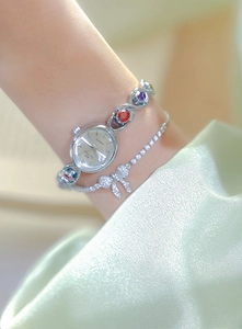 Close-up of silver watch featuring colorful gems and a zircon bow bracelet detail
