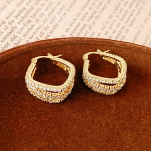Detailed macro view of gold geometric hoop earrings with dense cubic zirconia settings