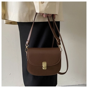Detail of a dark brown leather saddle bag with gold metal hardware on model