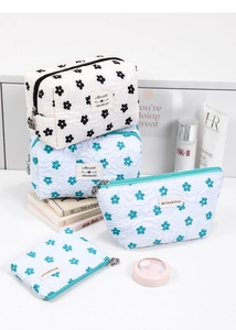 Detail of floral quilted cosmetic bags with flower zipper pull and brand tag