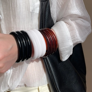 Detail of stacked resin bangles in black white and amber on a model wrist