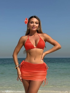 Detail of orange crochet mesh texture and drawstring design on the beach skirt and bikini set