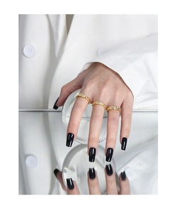 Detail of three gold textured rings with micro-set zircons on a hand with black nails