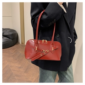 Detail of wine red patent leather handbag with gold hardware and buckle strap