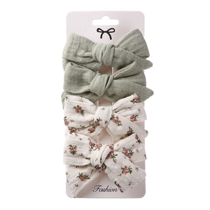 Close-up of 4-piece hair bow clip set featuring floral patterns and solid green fabric