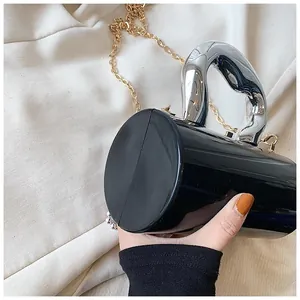 Close-up of black cylindrical acrylic bag featuring a bold silver oversized metal handle
