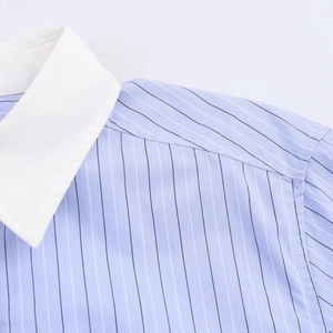 Detailed close-up of contrasting white collar and blue striped fabric stitching