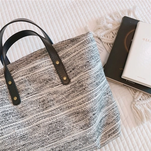 Vue détaillée du sac cabas tissé avec anses en cuir marron et rivets vintage
