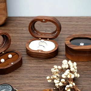 Detail of walnut wood jewelry boxes with clear glass lids and velvet lining on wooden table