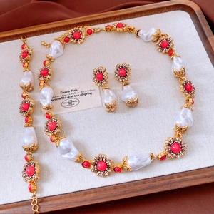 Details des Vintage-Schmucksets mit roten Blumen und Barockperlen auf Leinen