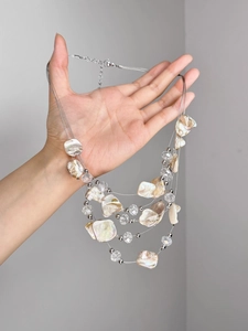 Détail d'un collier bohème multicouche avec perles de coquillage et pendentifs cristal