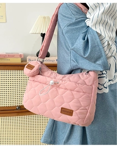 Détail du sac bandoulière en nylon matelassé rose avec petite pochette amovible et étiquette