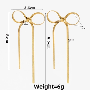 Vue détaillée des boucles d'oreilles nœud doré avec pompons et dimensions précises