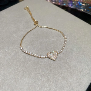 Detail of gold heart pendant bracelet with sparkling cubic zirconia and adjustable slide clasp