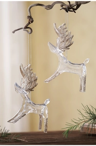 Detail of two glittery reindeer ornaments hanging on a pine branch for Christmas decor