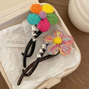 Close-up of woven flower hair clips with heart-shaped rhinestones and resin finish