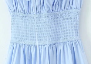Détail macro du smock élastique sur une robe en coton bleu clair pour une coupe ajustée