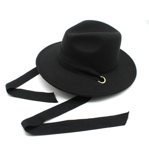 Detail of vintage black wool fedora featuring a long side ribbon and golden metal ring accent