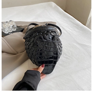 Close-up of a stylish black owl-shaped crossbody bag with crocodile embossed texture