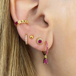 Macro shot of gold geometric earrings set featuring rose red gemstones and cubic zirconia