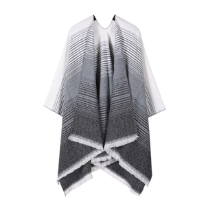 Detail of knit shawl featuring grey gradient stripes and soft tassel fringe textures