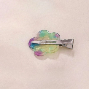 Detail of flower-shaped hair clip with iridescent resin petals and a metal duckbill clip