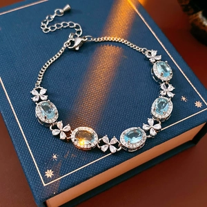 Detailed close-up of zircon flower bracelet with blue oval gems on dark gift box