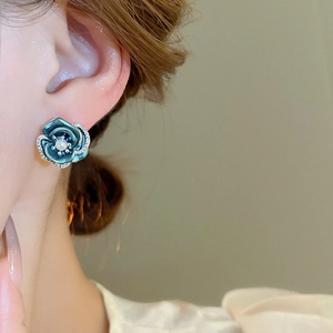Close-up of blue floral earring with pavé rhinestones and a central pearl on model