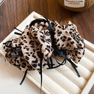 Detail of leopard print fabric hair scrunchie with black ribbon on a white jewelry tray