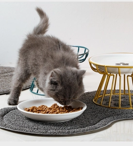 Macro detail of white ceramic cat bowl with golden metal stand and grey non-slip mat
