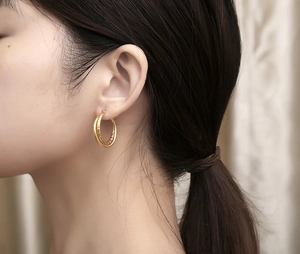 Close-up of double-layered gold ring earrings with intricate textured inner band detailing