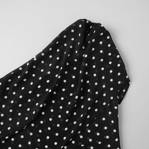 Gros plan sur un tissu en mousseline noire semi-transparente avec motif à pois blancs