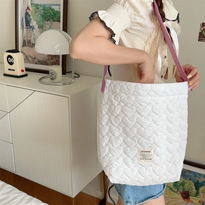 Detail of white quilted tote bag with heart patterns and contrasting purple strap